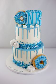 a three tiered cake with blue icing and frosting sprinkles