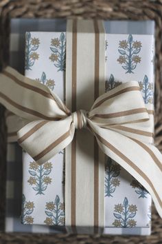 two wrapped presents tied up in brown and white ribbons on a wicker basket with twine