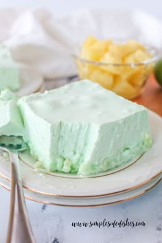 a piece of cake on a plate with a fork and bowl of fruit in the background