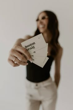 a woman holding up two business cards in her hand