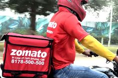 a man riding on the back of a motorcycle next to a red bag with yellow sleeves