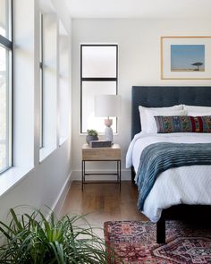 a bedroom with a bed, nightstands and plants on the side table in front of it