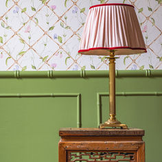 a lamp sitting on top of a wooden table next to a wall with green paint