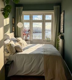 a bedroom with a large bed and two windows overlooking the water in front of it