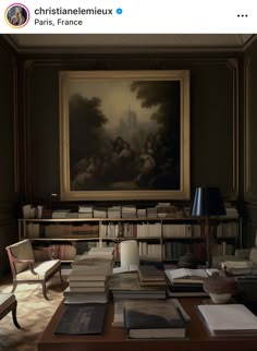 a table with many books on it in front of a painting