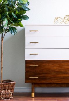 a white and brown dresser next to a potted plant