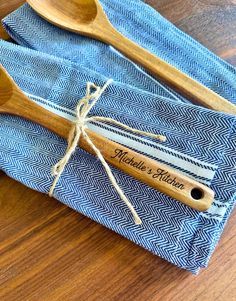 two wooden spoons are sitting on top of blue napkins with a name tag