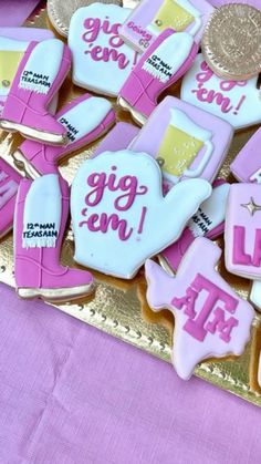 cookies decorated with pink and white icing on a gold tray next to a purple table cloth