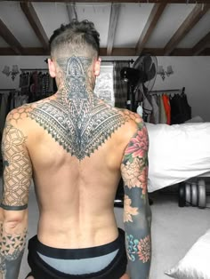 a man with lots of tattoos on his back and chest is sitting in a room