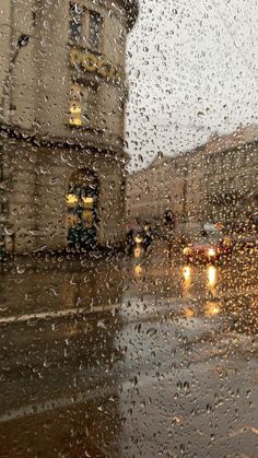 rain is falling on the window and cars are driving down the street in the city