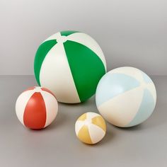 three beach balls and one ball are on the floor in front of a gray background