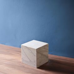 a marble block sitting on top of a hard wood floor next to a blue wall