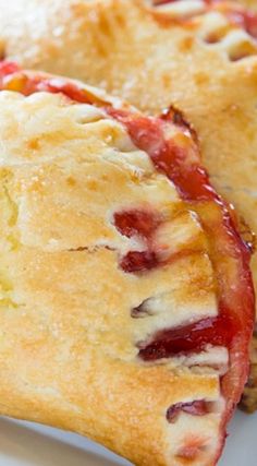 two pastries sitting on top of a white plate next to each other with strawberries in them