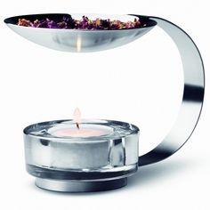 a candle that is sitting on top of a glass holder with a metal handle and light in the middle