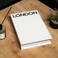 a white box sitting on top of a wooden table next to a candle and potted plant