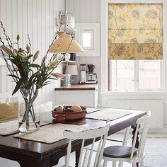 a dining room table with chairs and a vase filled with flowers on top of it