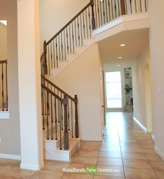 a staircase leading up to the second floor in a house with beige walls and tile floors