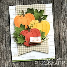 a card with pumpkins and leaves on it, in front of a wooden background