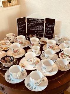 a table topped with lots of tea cups and saucers on top of a wooden table