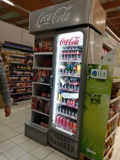 a vending machine in a grocery store filled with drinks and sodas on display