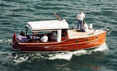 a man standing on top of a wooden boat in the middle of the ocean with other people