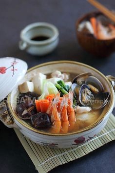 a bowl of soup with shrimp, carrots and mushrooms