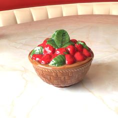 a ceramic bowl filled with strawberries on top of a table