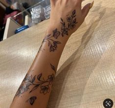 a woman's arm with flowers on it and a tattoo design on the wrist