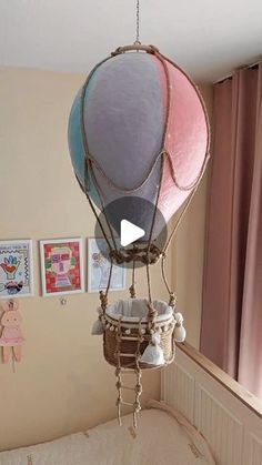 a baby crib with a hot air balloon hanging from it's side and pictures on the wall