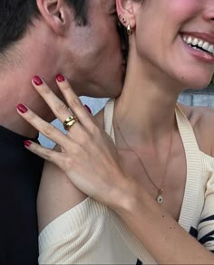 a man and woman kissing each other with their hands on her chest, both wearing gold rings