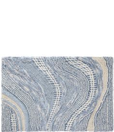 a blue and white rug with wavy lines on the bottom, in front of a white background