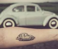 a small tattoo on the arm of a person with a car in the back ground