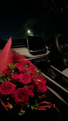 a bunch of red roses sitting on the dashboard of a car