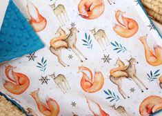 a blanket with foxes and snowflakes on it next to a wicker basket