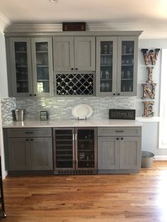 a kitchen with gray cabinets and wood floors in the center is an open wine rack