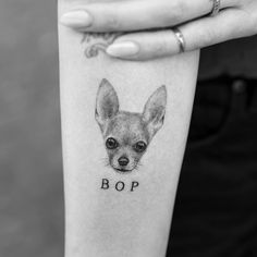 a woman's arm with a small dog tattoo on it