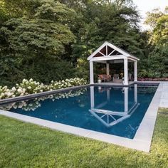 a pool with a gazebo next to it in the middle of some grass and trees