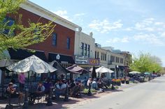 people are sitting at tables outside on the sidewalk