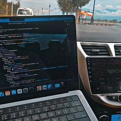 a laptop computer sitting on top of a car dashboard