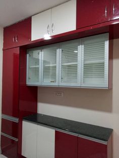 a kitchen with red and white cupboards, black counter tops, and an oven