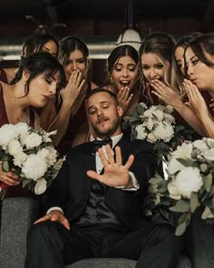 a group of bridesmaids and groomsmid posing for a photo with their hands in the air