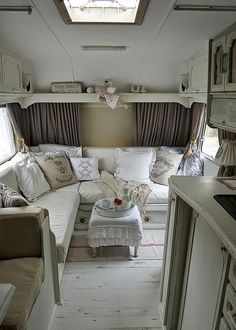 a living area with couches, tables and windows in an airstream style home