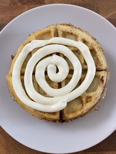 a white plate topped with a waffle covered in icing on top of a wooden table