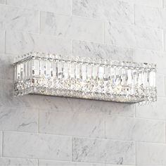 a crystal wall light mounted on the side of a white brick wall in a bathroom