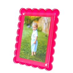 a little boy standing in the grass with a pink frame on it's side