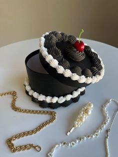 there is a black cake on the table with pearls and a chain next to it