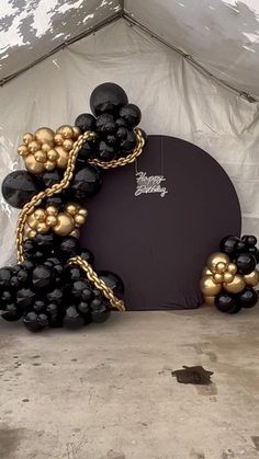 a black and gold balloon arch is set up in front of a white canvas tent