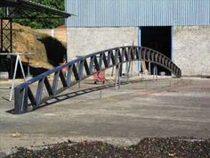 a long metal bridge going across a parking lot next to a building with blue doors