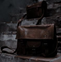 a brown leather messenger bag sitting on some steps