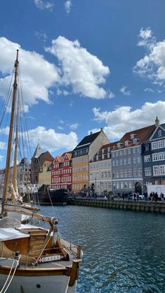 several boats are docked in the water next to some buildings and blue sky with white clouds